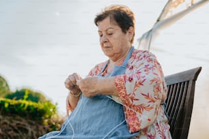 a woman sitting on a chair knitting a piece of fabric