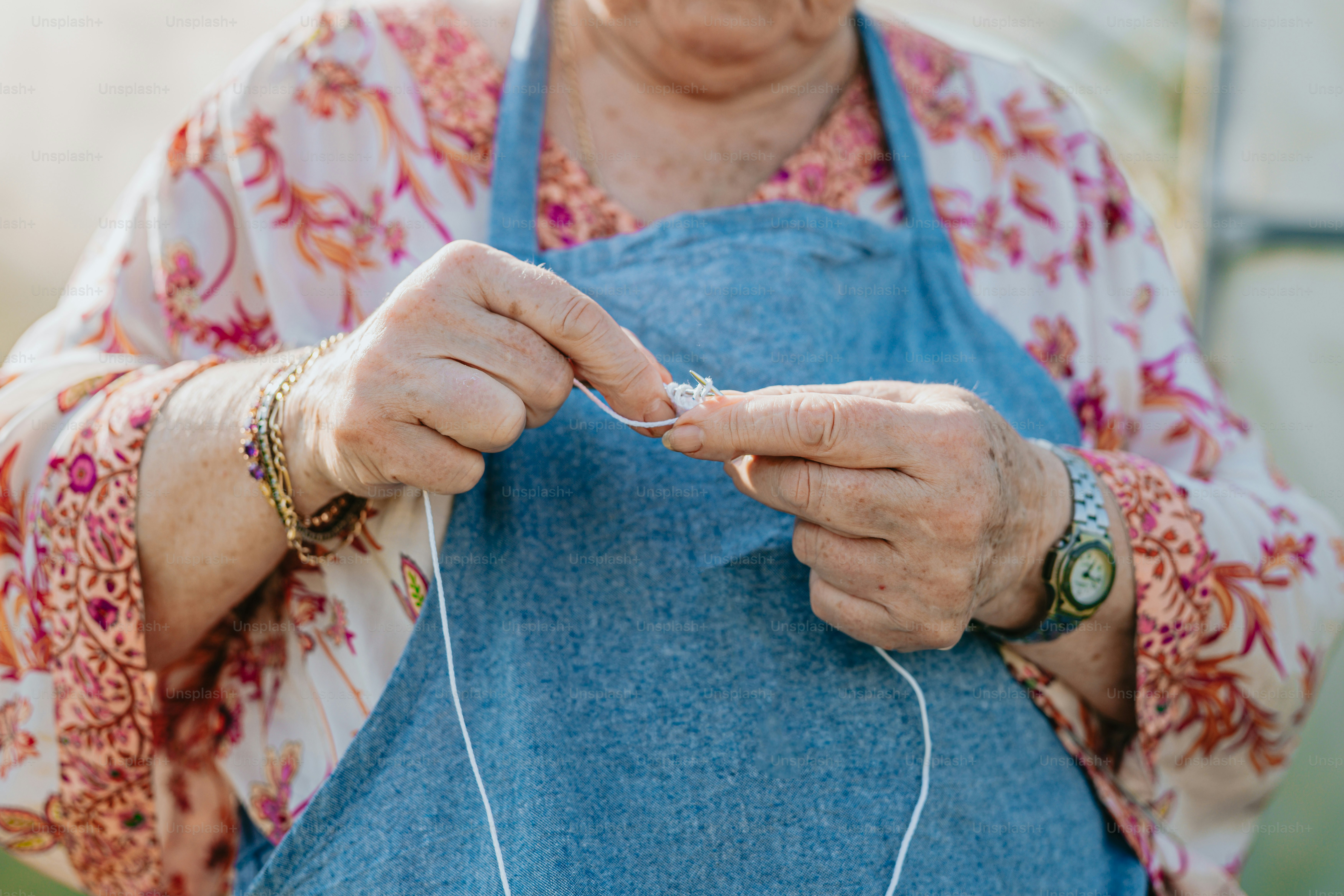 an elderly woman is knitting a piece of fabric