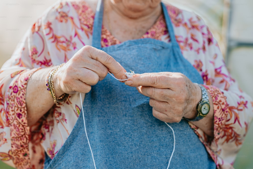 an elderly woman is knitting a piece of fabric