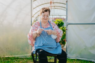 a woman sitting in a chair in a greenhouse