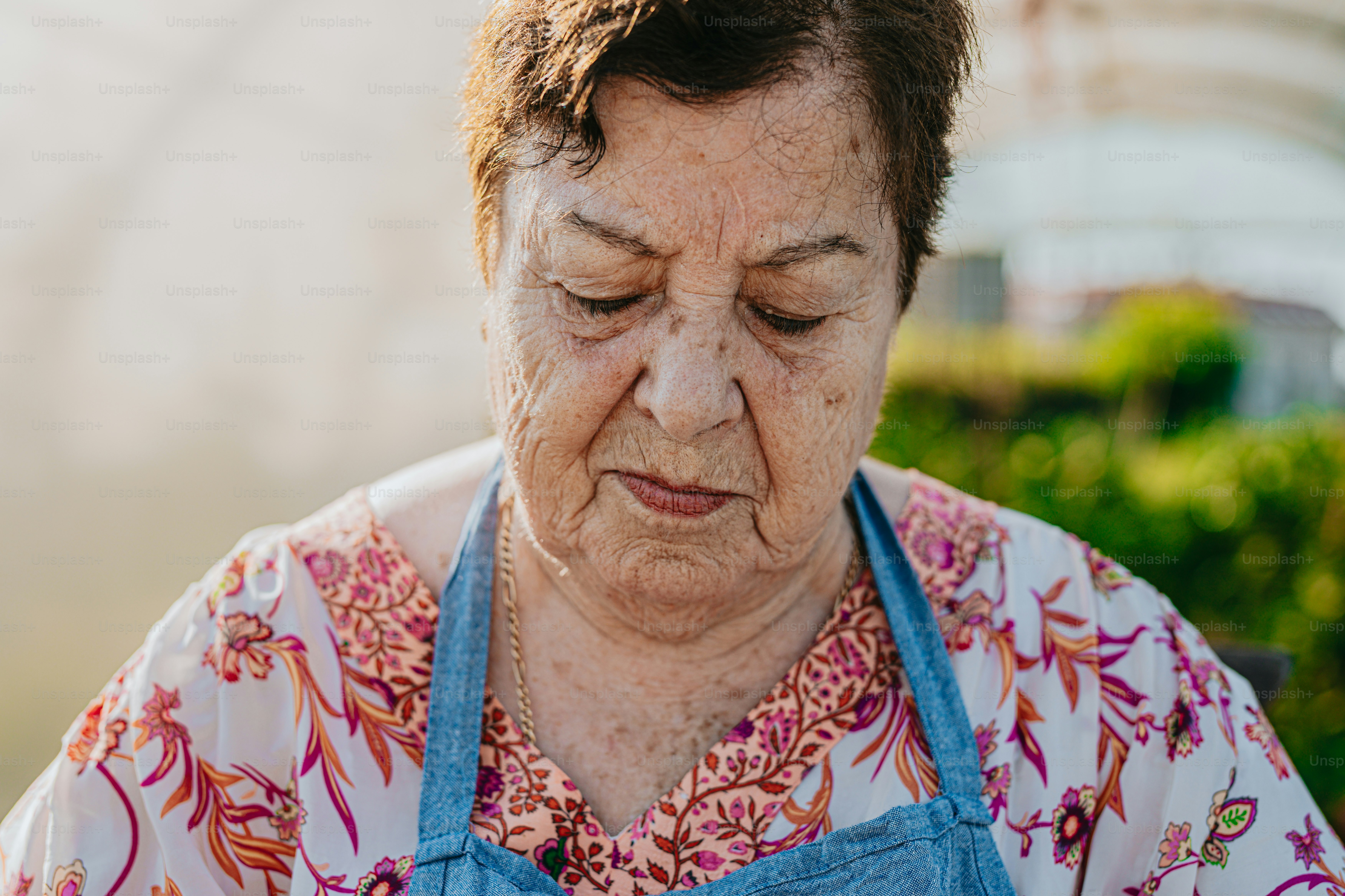 An older woman wearing a blue apron looking down photo – Elderly Image ...