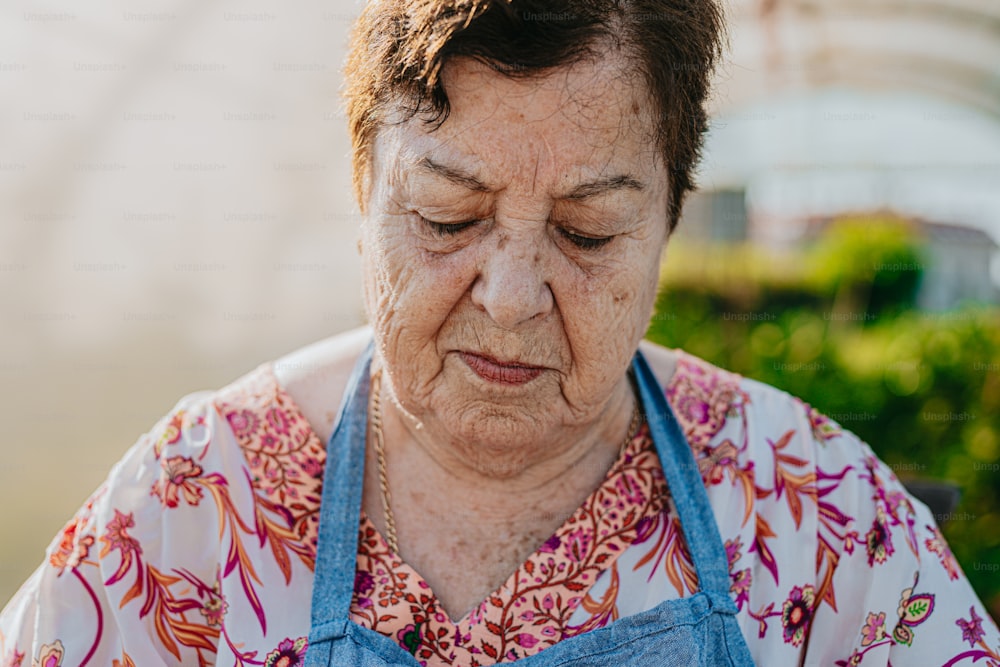 Una donna anziana che indossa un grembiule blu che guarda in basso