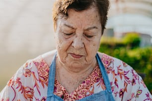 an older woman wearing a blue apron looking down