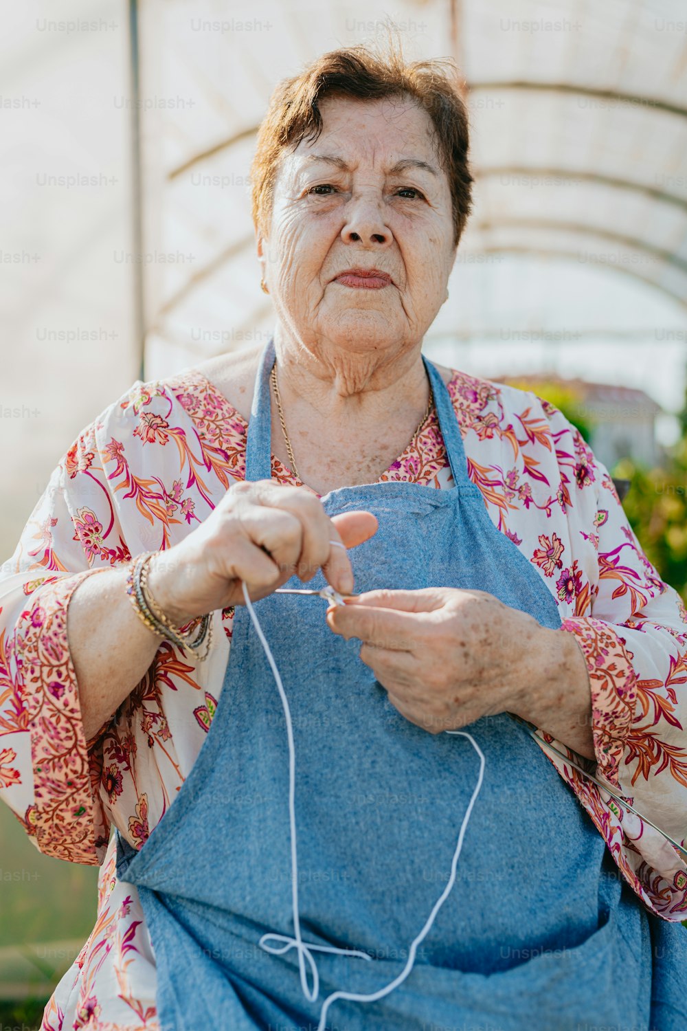 an older woman wearing an apron and holding a pair of scissors