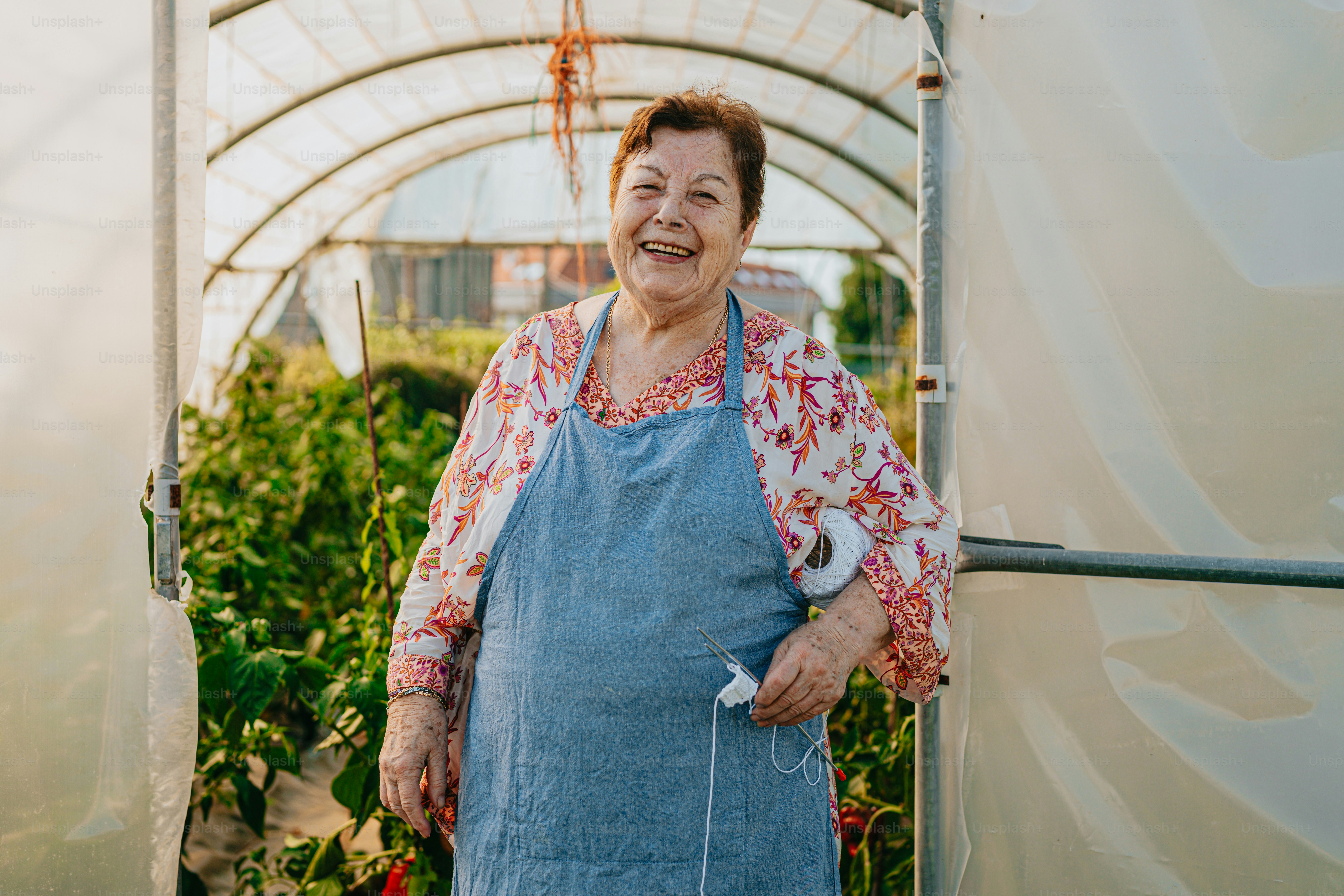 a woman in a blue apron standing in a greenhouse