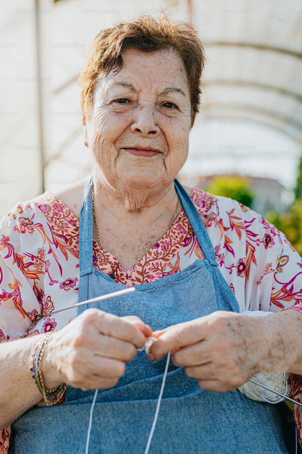 Una donna anziana che lavora a maglia un pezzo di stoffa