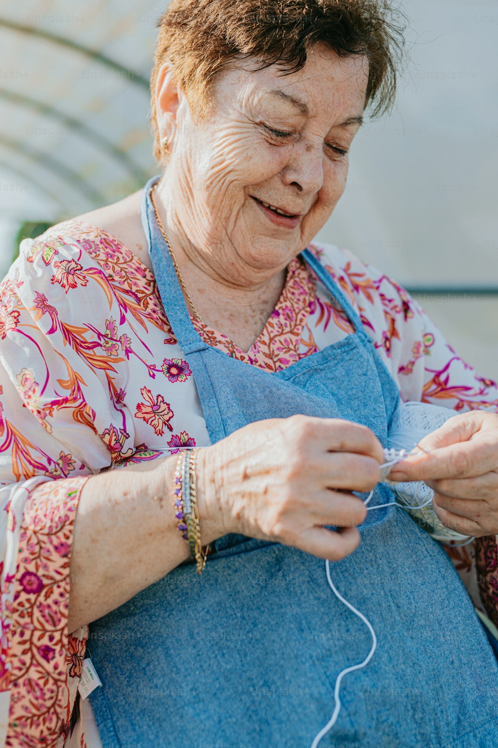 Una donna anziana sta lavorando a maglia un pezzo di stoffa