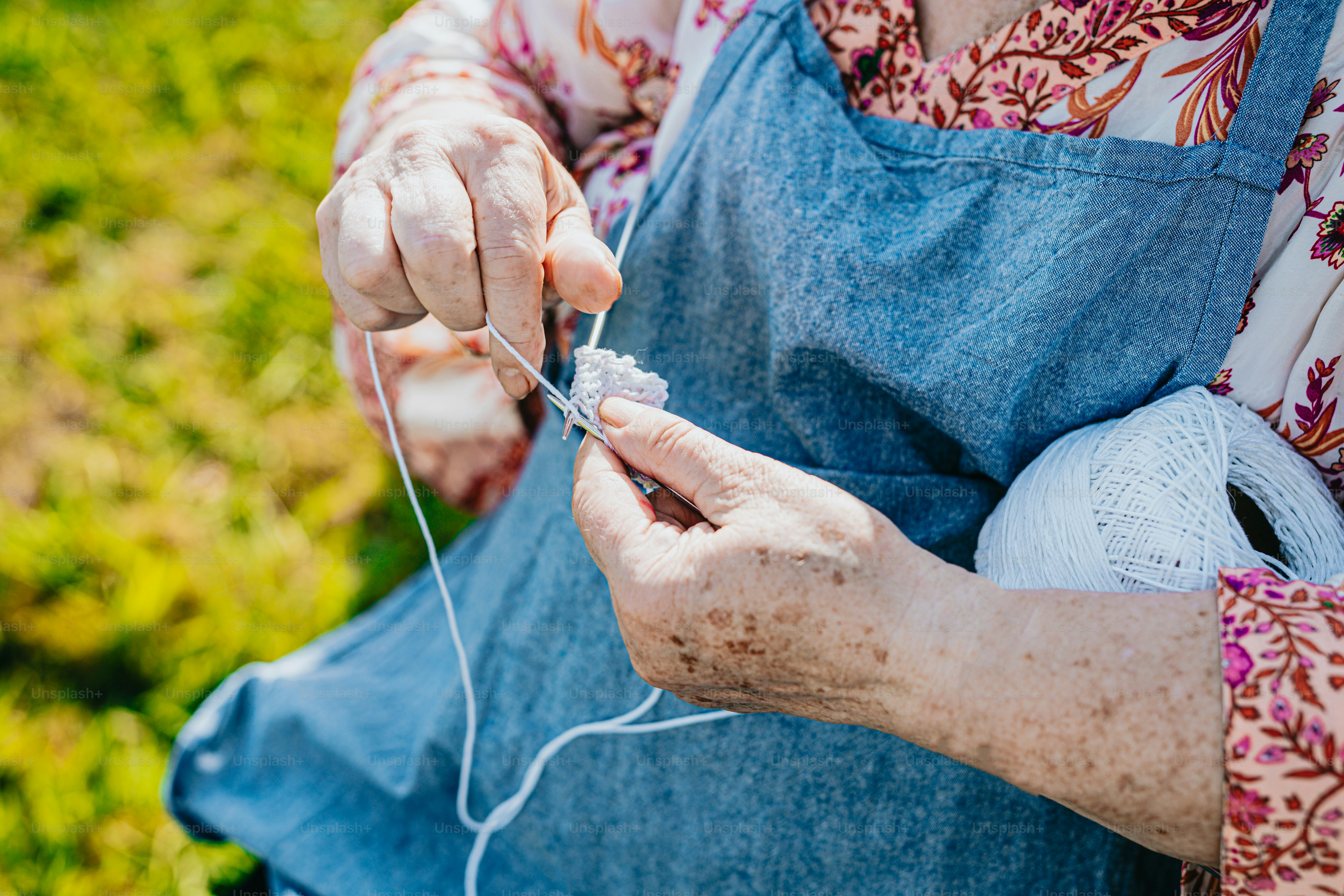 a woman is knitting a piece of fabric with a pair of scissors
