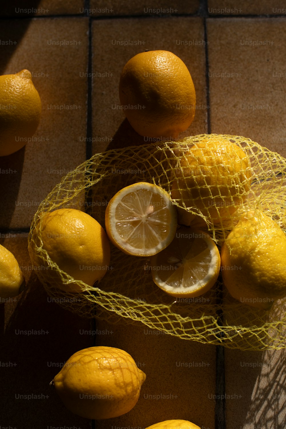 a mesh bag filled with lemons on top of a tiled floor