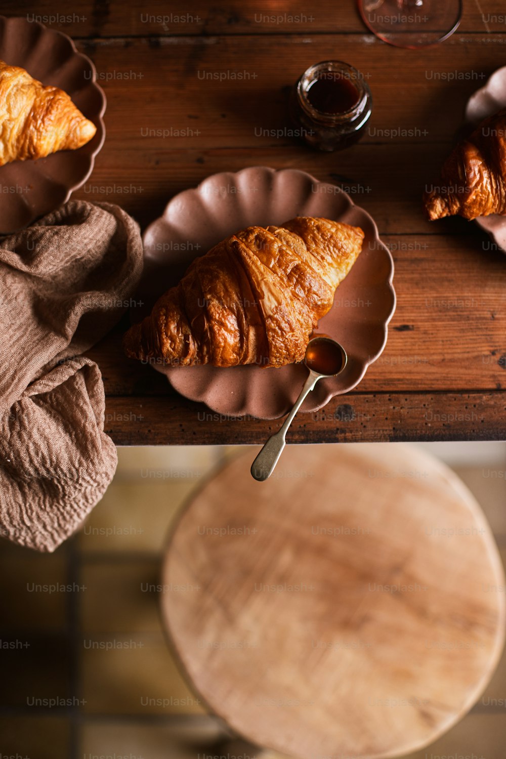 a wooden table topped with two croissants and a cup of coffee