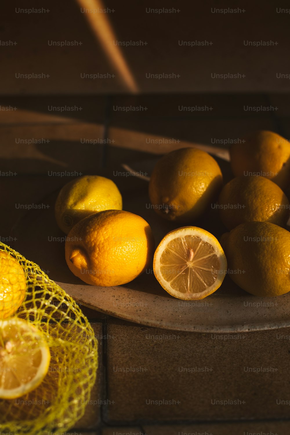 a bowl of lemons and a mesh bag of oranges