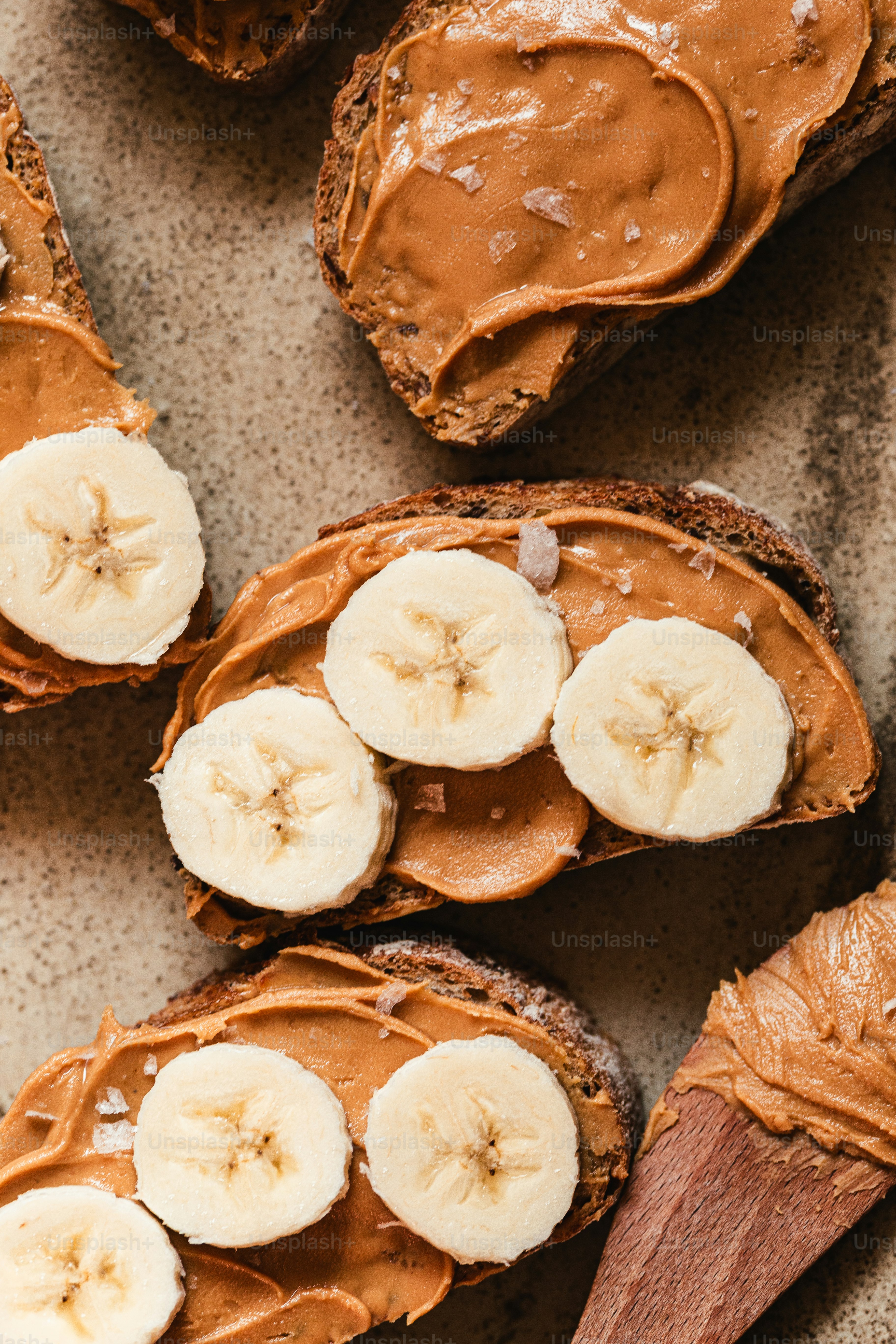 Beurre d’arachide et tranches de banane sur pain grillé avec une cuillère en bois