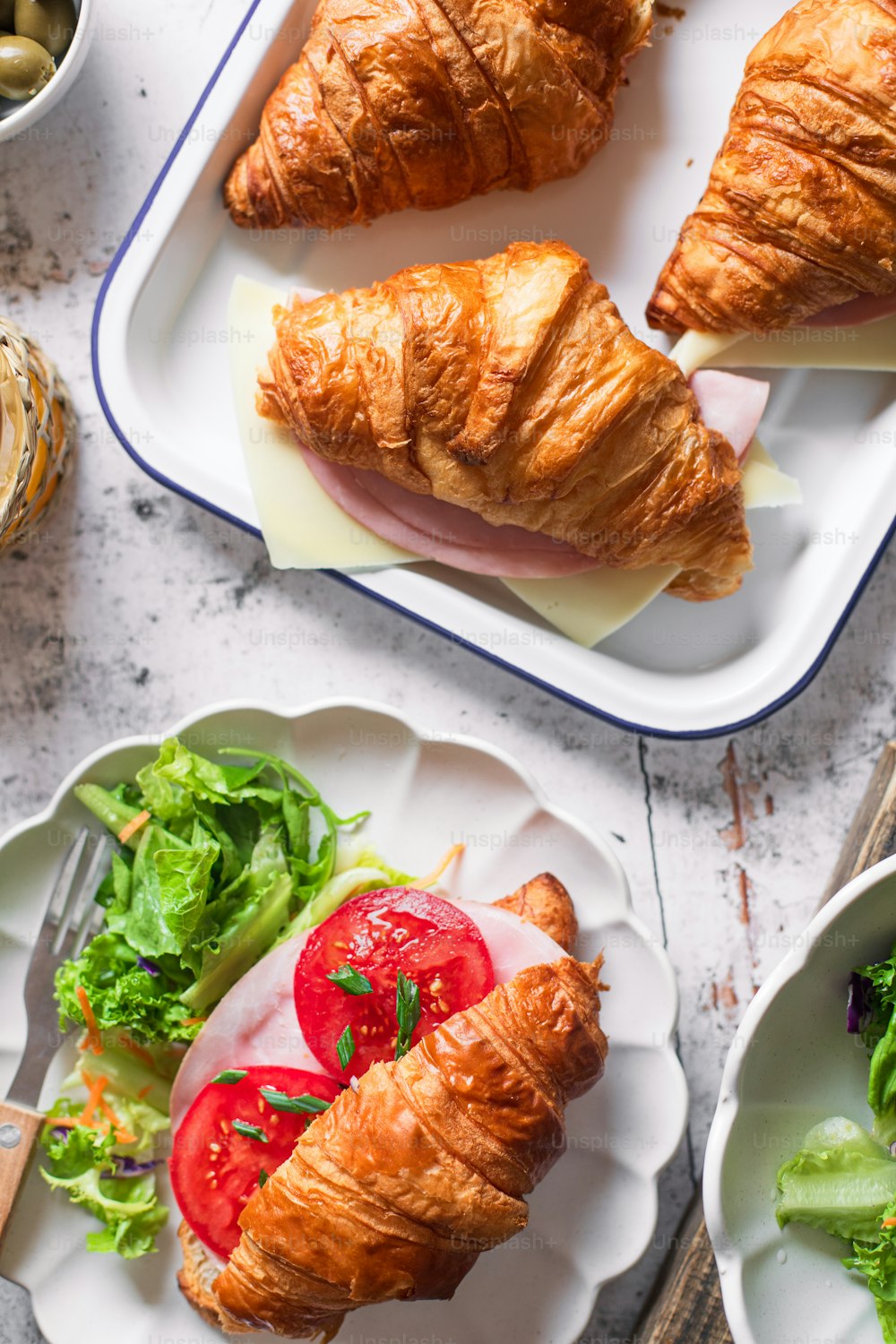 croissants, salad, and bread on plates on a table