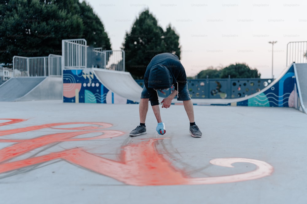 a man bending over on a skateboard at a skate park