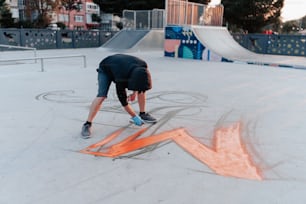 a person bending over on a skateboard in a skate park