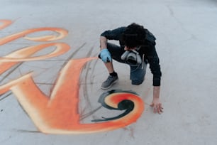 a man kneeling down on a skateboard in front of graffiti