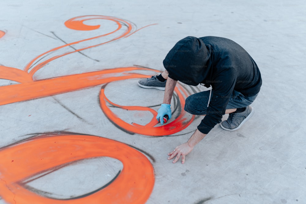 a man is painting the letters orange on the ground