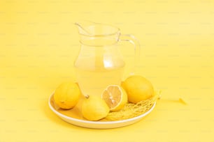 una jarra de agua y algunos limones en un plato