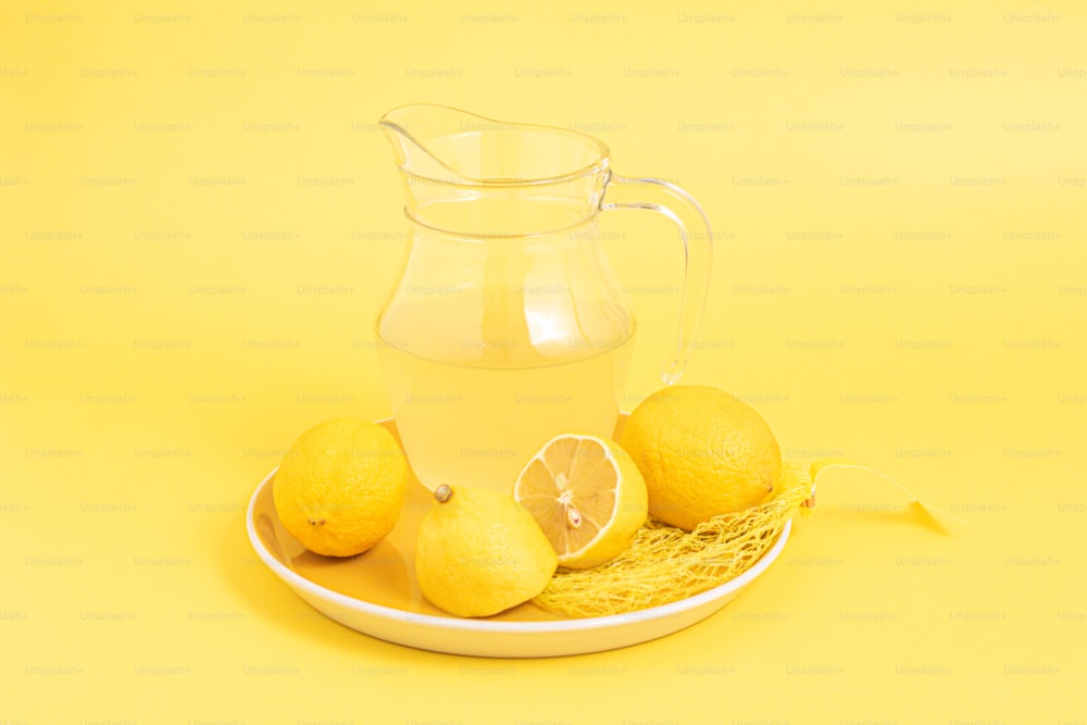 a pitcher of water and some lemons on a plate