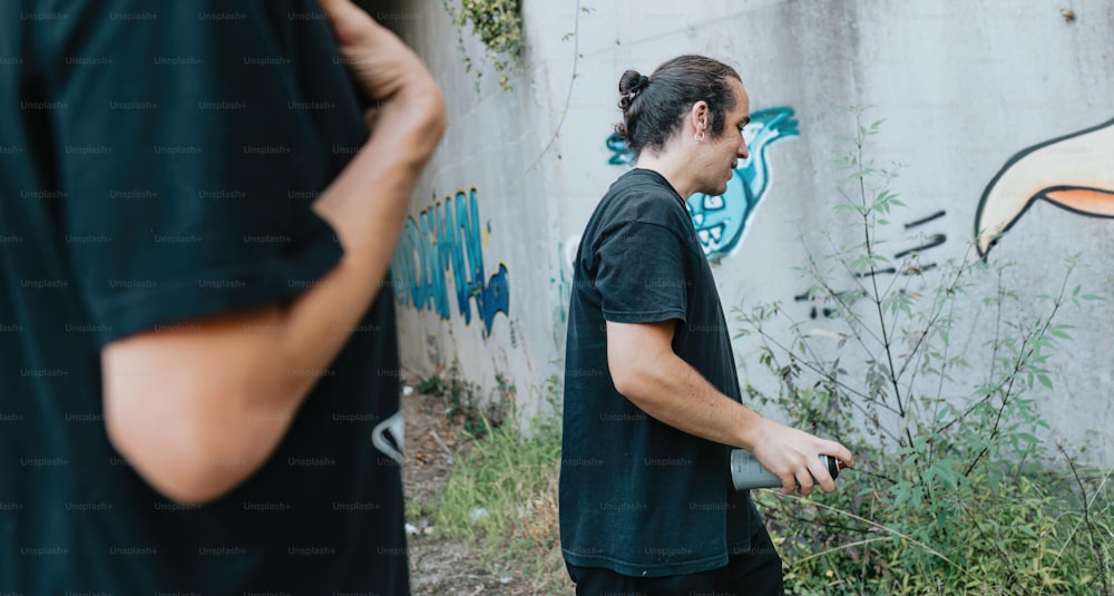 a man standing next to a wall with graffiti on it