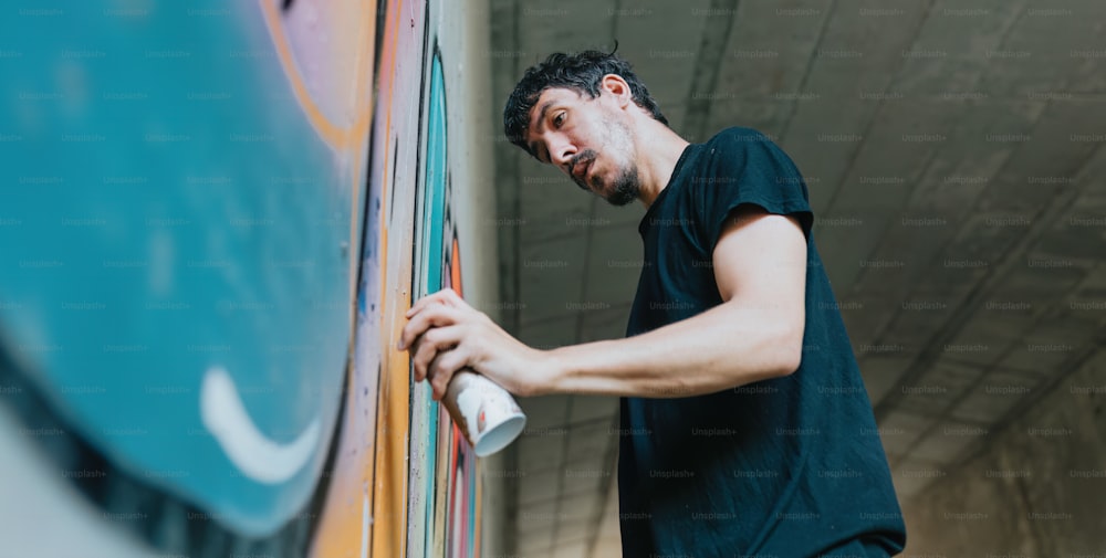 Un uomo sta dipingendo un murale su un muro