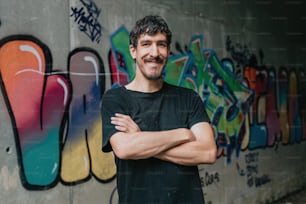 Un uomo in piedi davanti a un muro coperto di graffiti