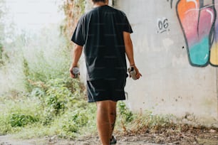 a man walking past a graffiti covered wall