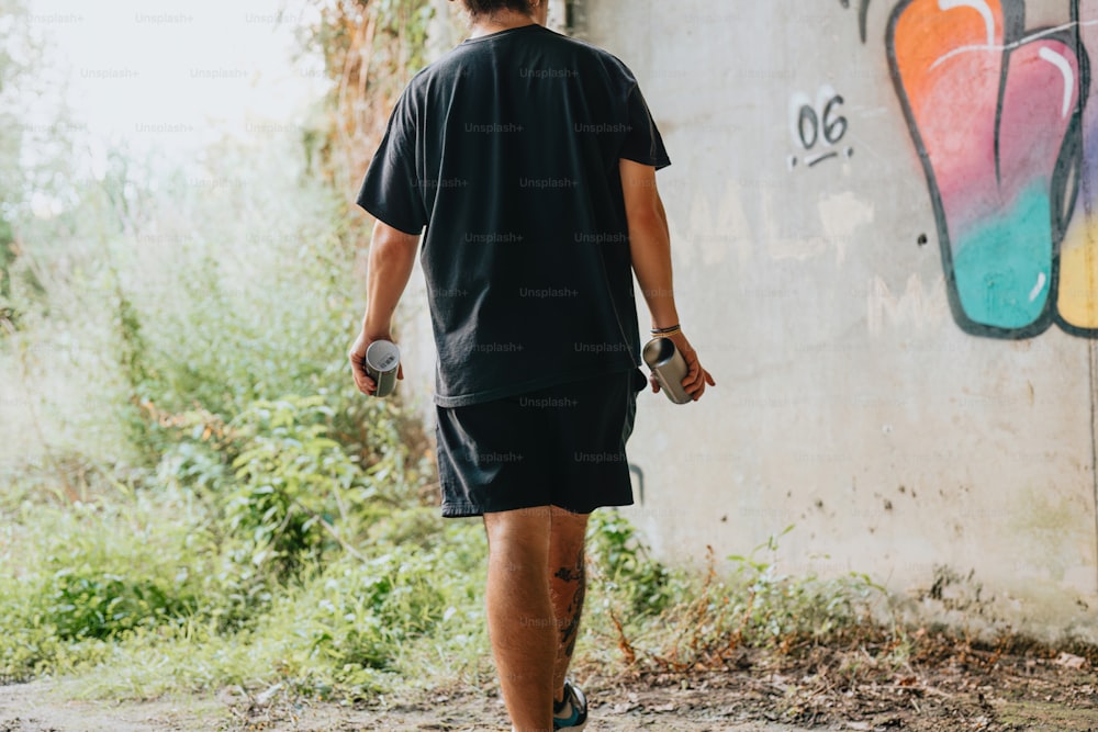 Un uomo che cammina oltre un muro coperto di graffiti