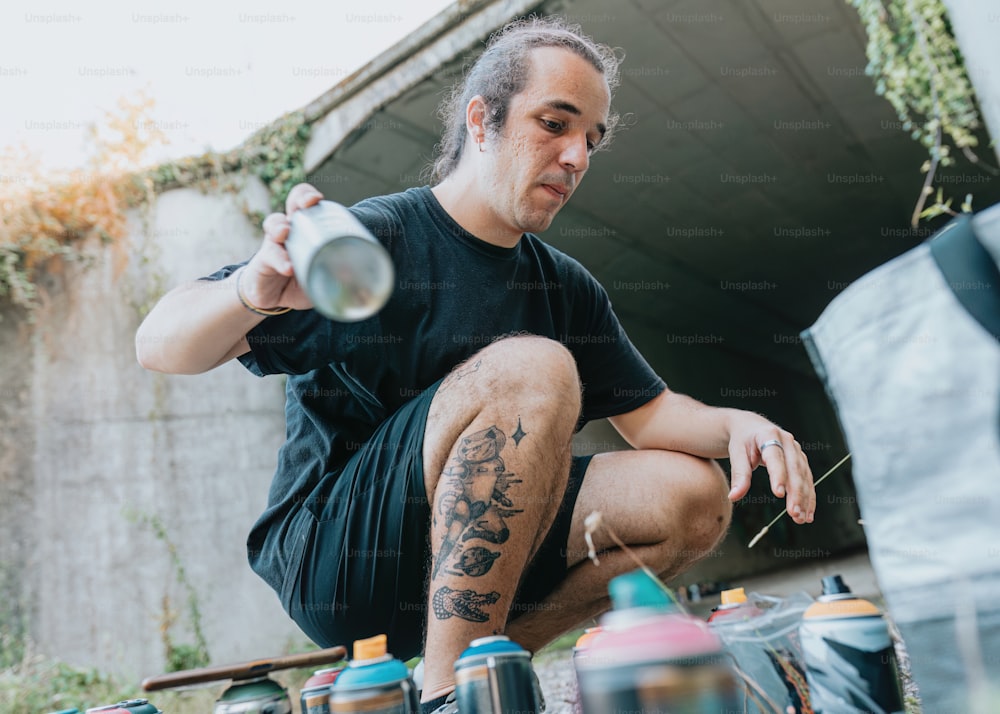 a man sitting on the ground holding a can of spray paint