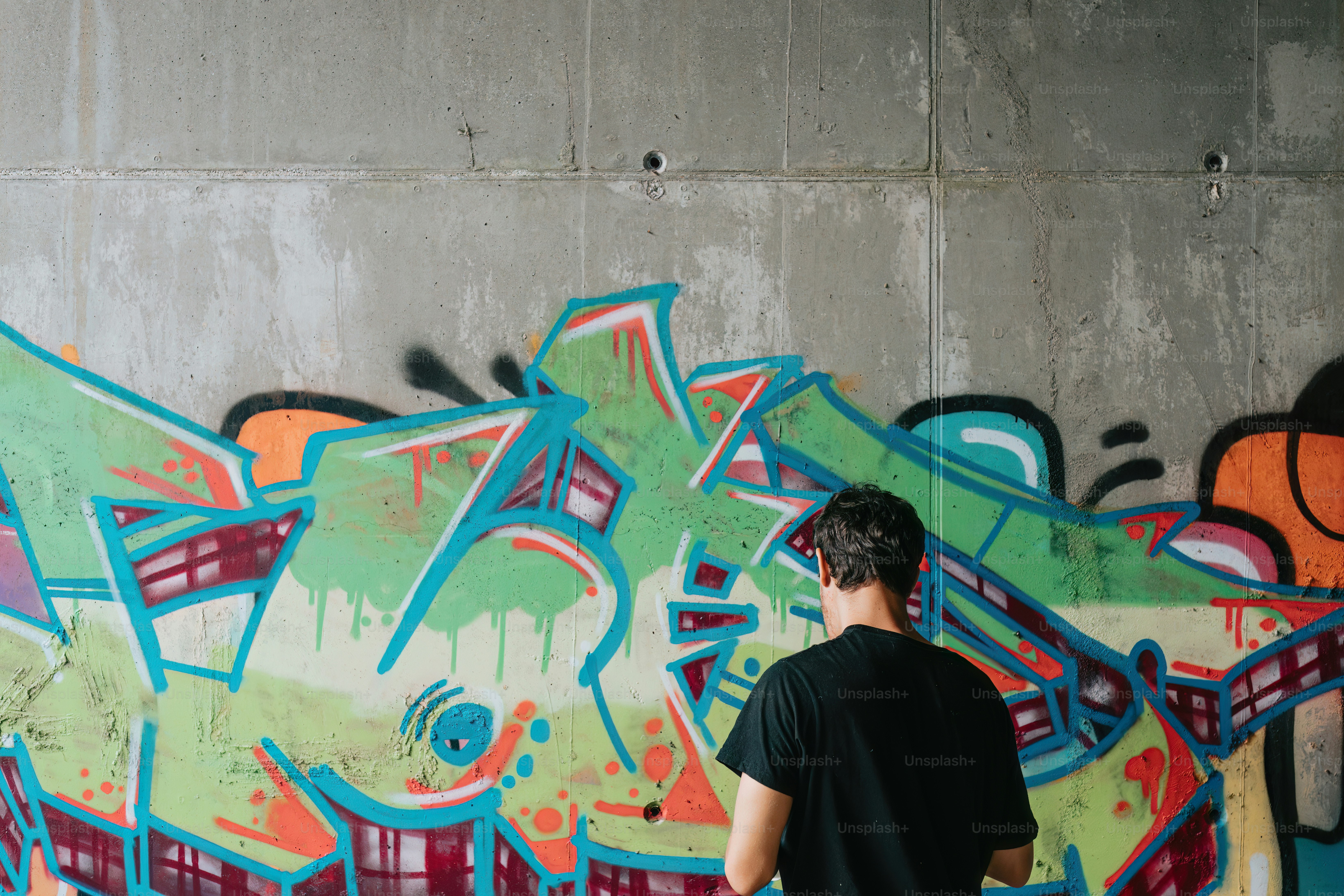 a man standing in front of a graffiti covered wall