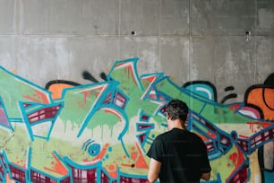 a man standing in front of a graffiti covered wall