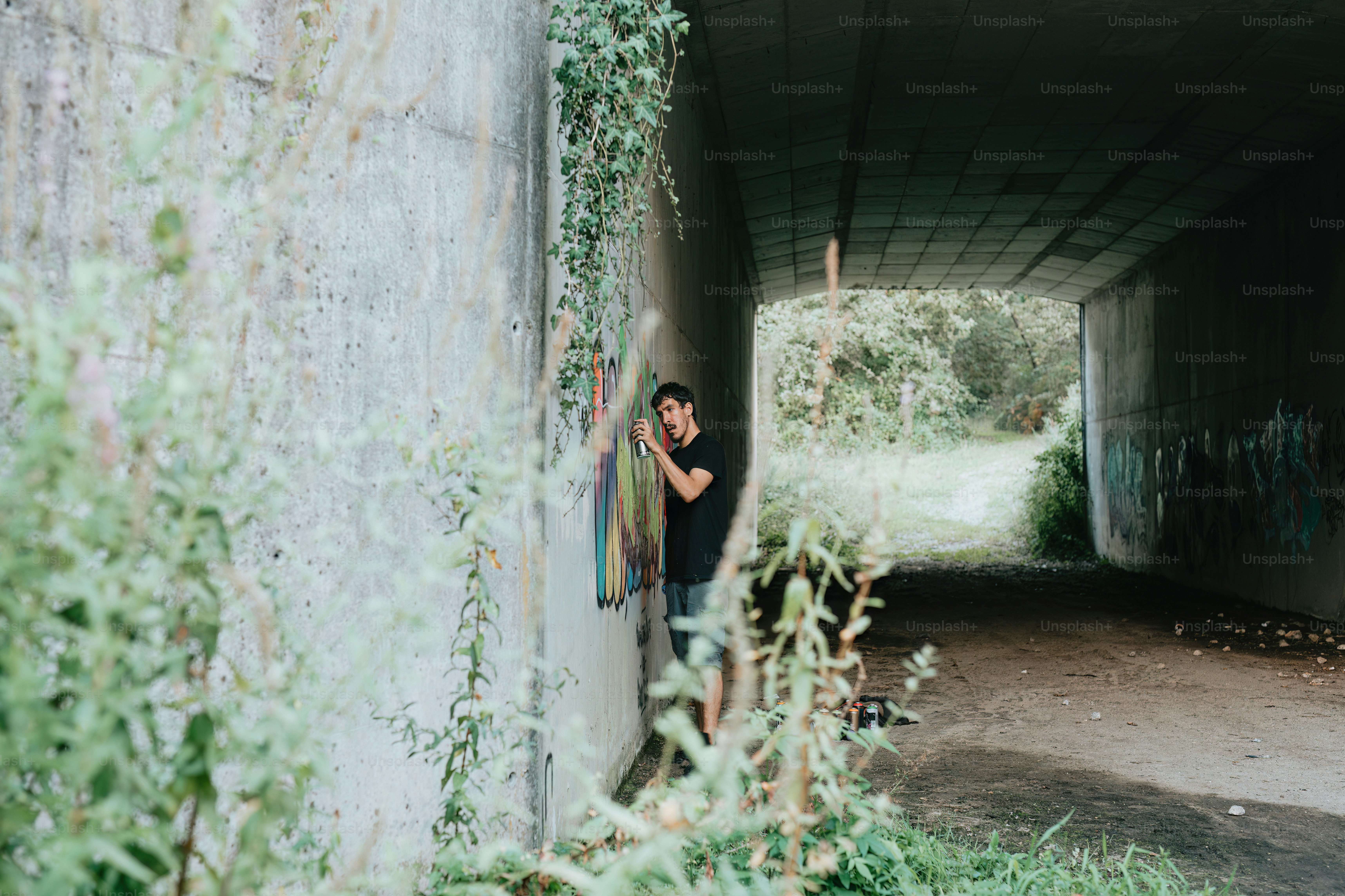 a man leaning against a wall in a tunnel