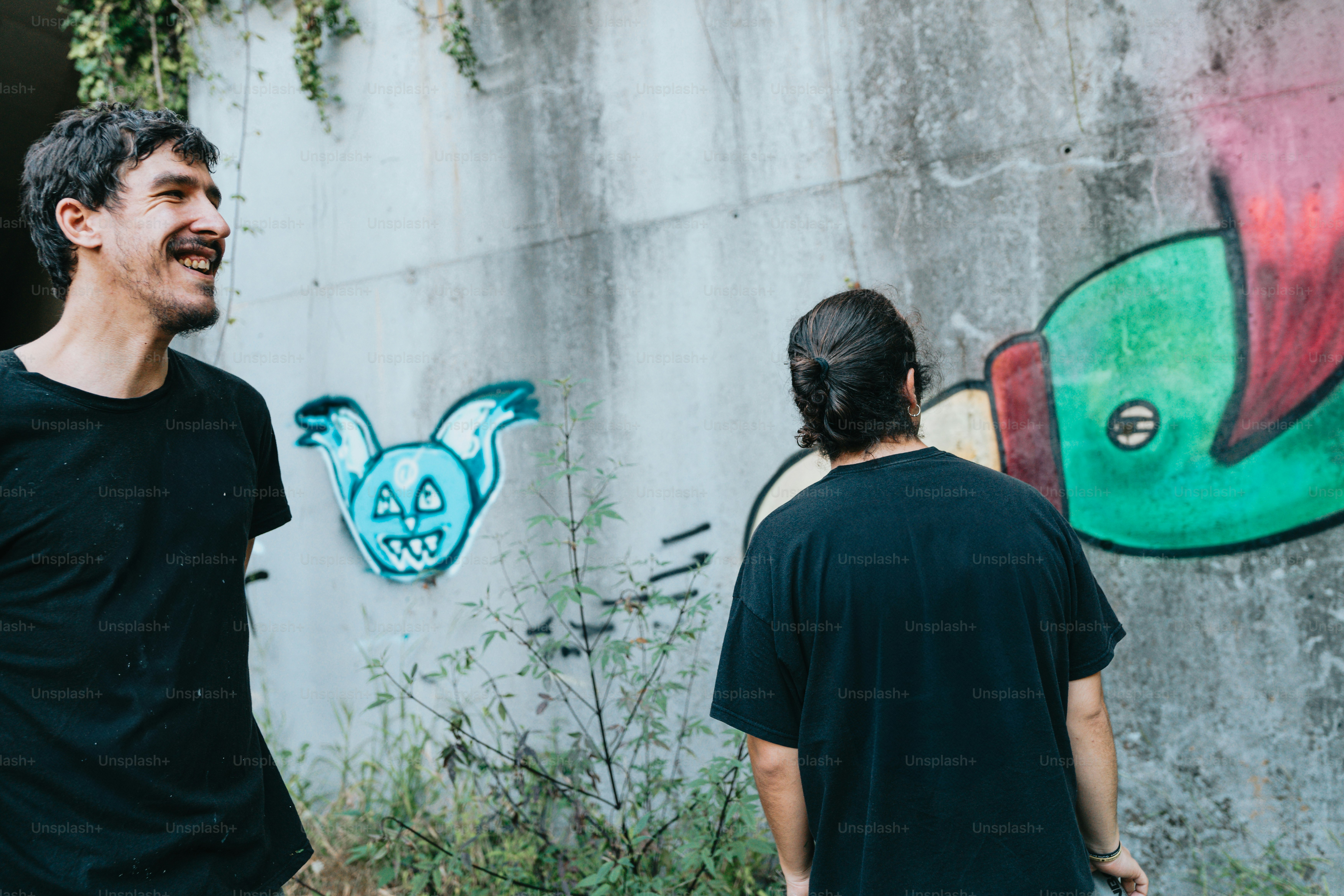 a man and a woman standing in front of a wall with graffiti