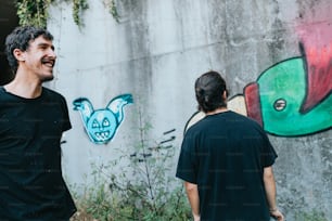 a man and a woman standing in front of a wall with graffiti