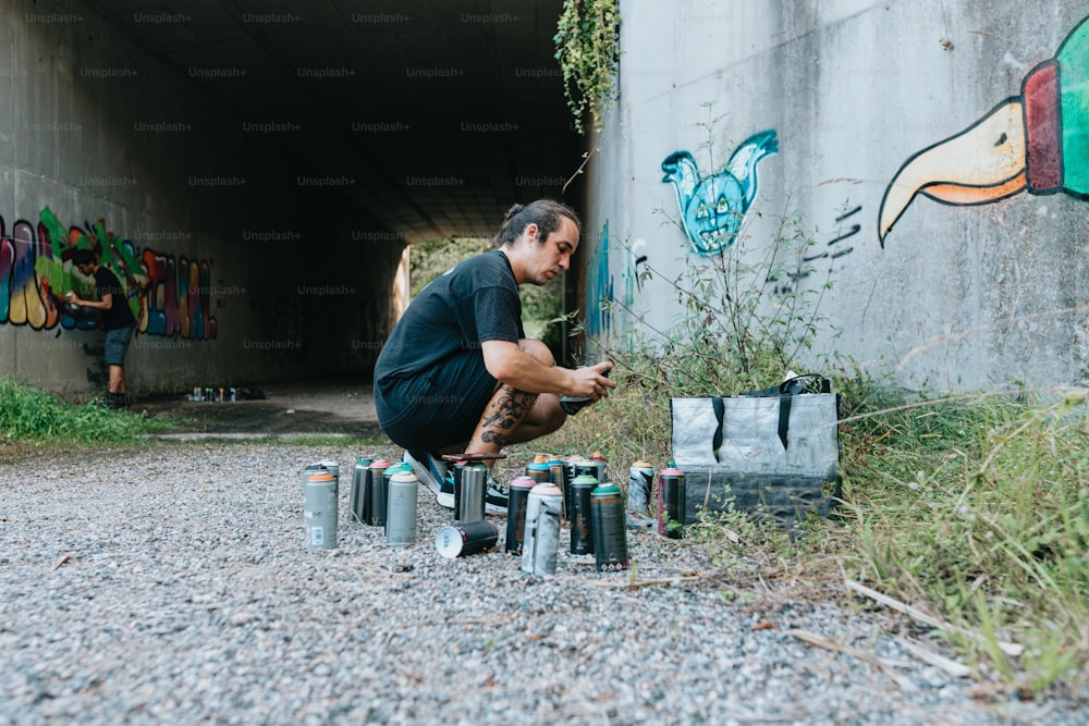 a man kneeling down next to a bunch of cans