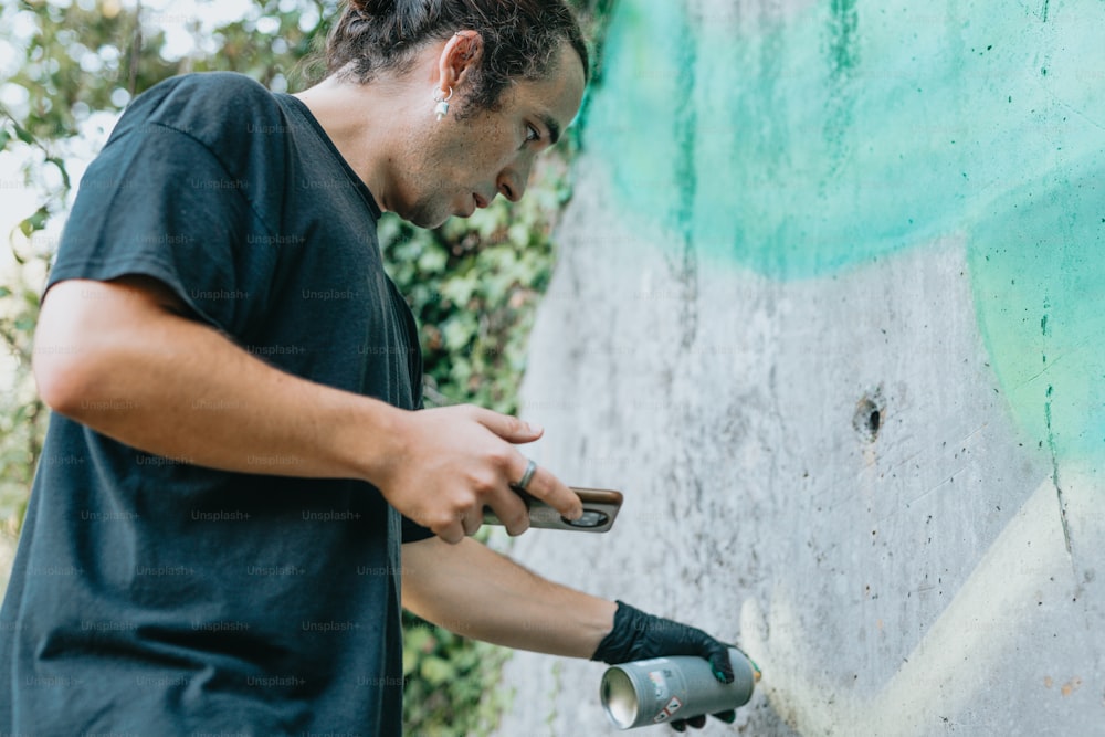 a man holding a cell phone next to a wall