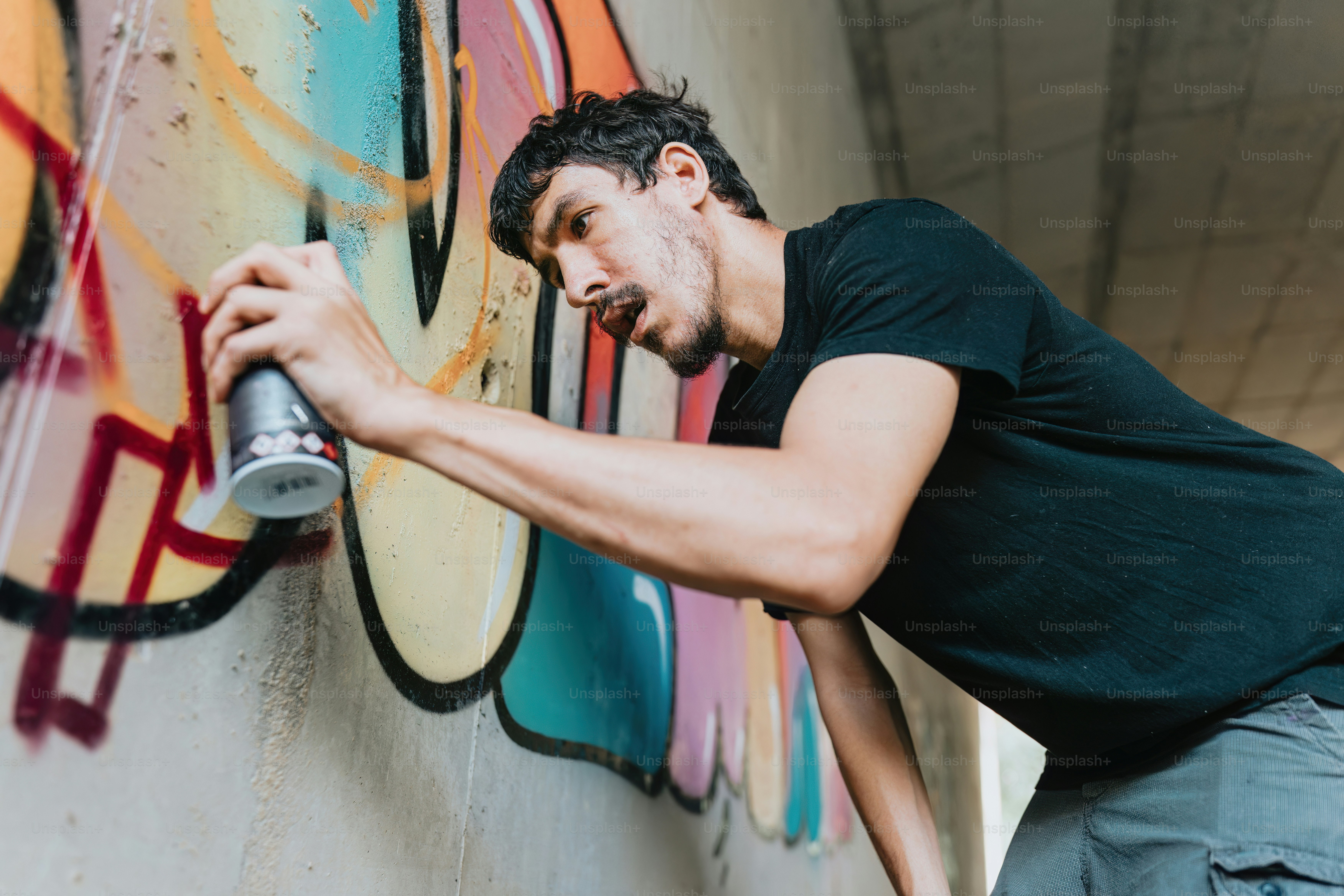 a man spray painting on a wall with graffiti