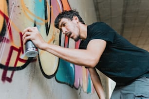 a man spray painting on a wall with graffiti