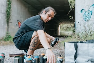 a man kneeling down next to a bunch of cans