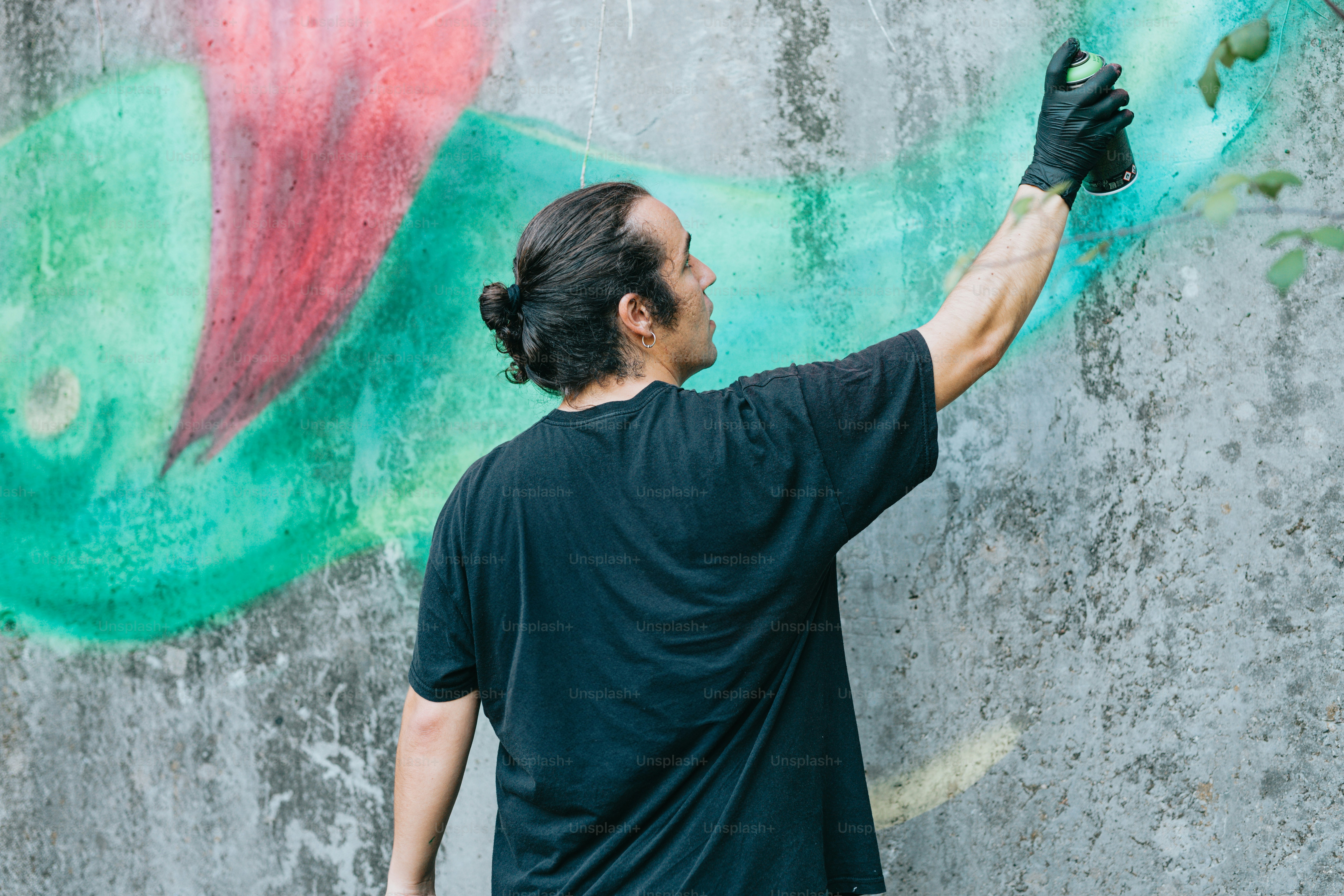 A man painting graffiti on a wall with roller skates photo – Art Image ...