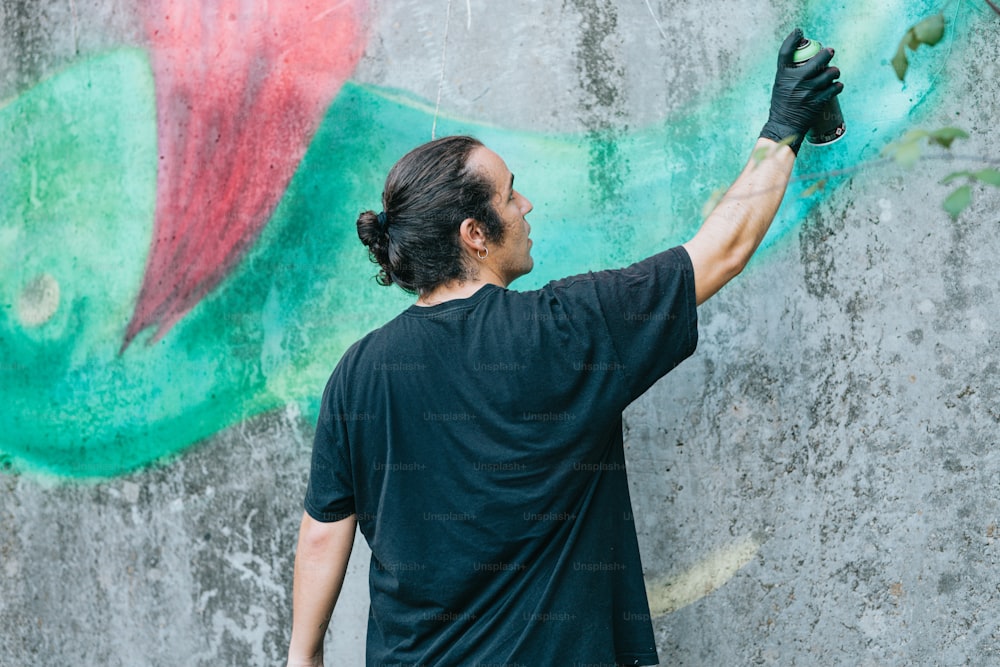 Ein Mann im schwarzen Hemd malt eine Wand