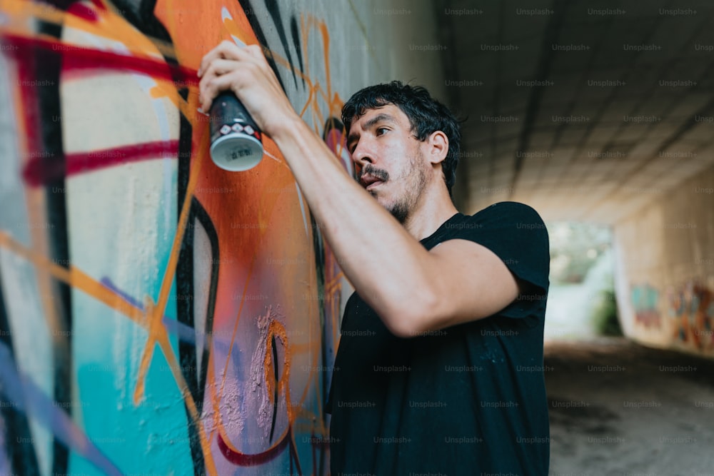 한 남자가 낙서로 벽을 스프레이로 칠하��고 있다