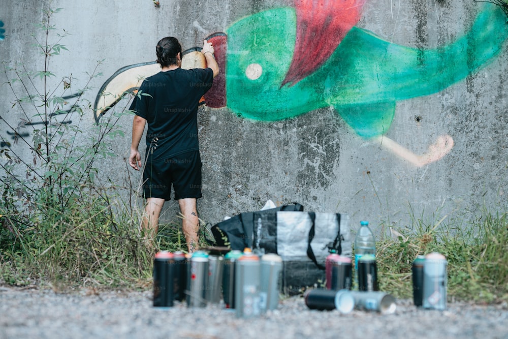 Un homme peignant une peinture murale sur le côté d’un bâtiment