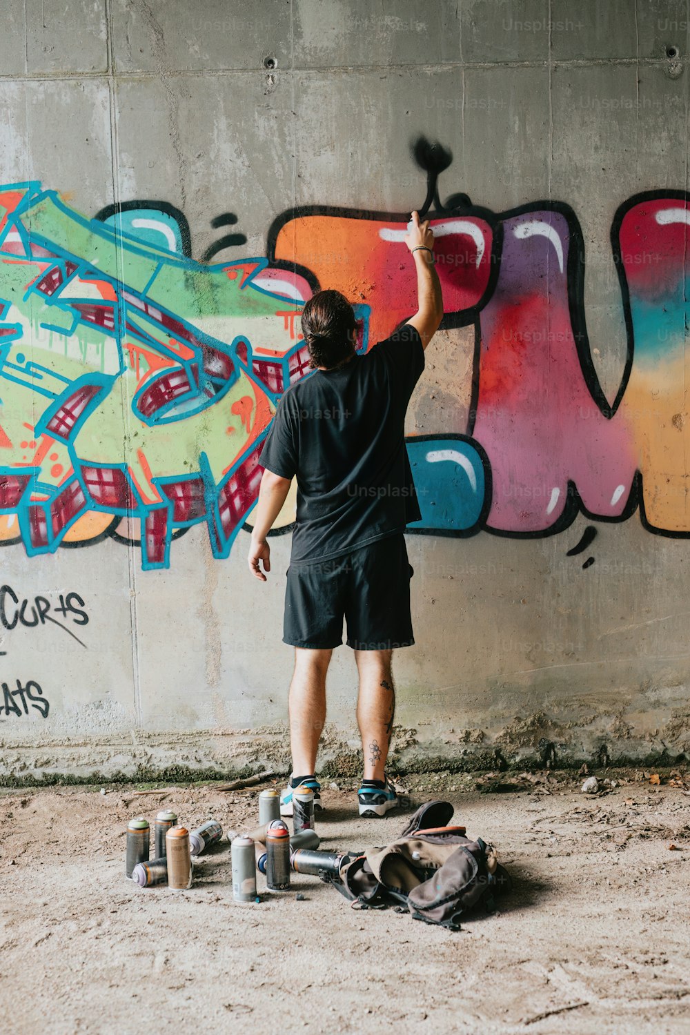 a man painting graffiti on a wall with roller skates