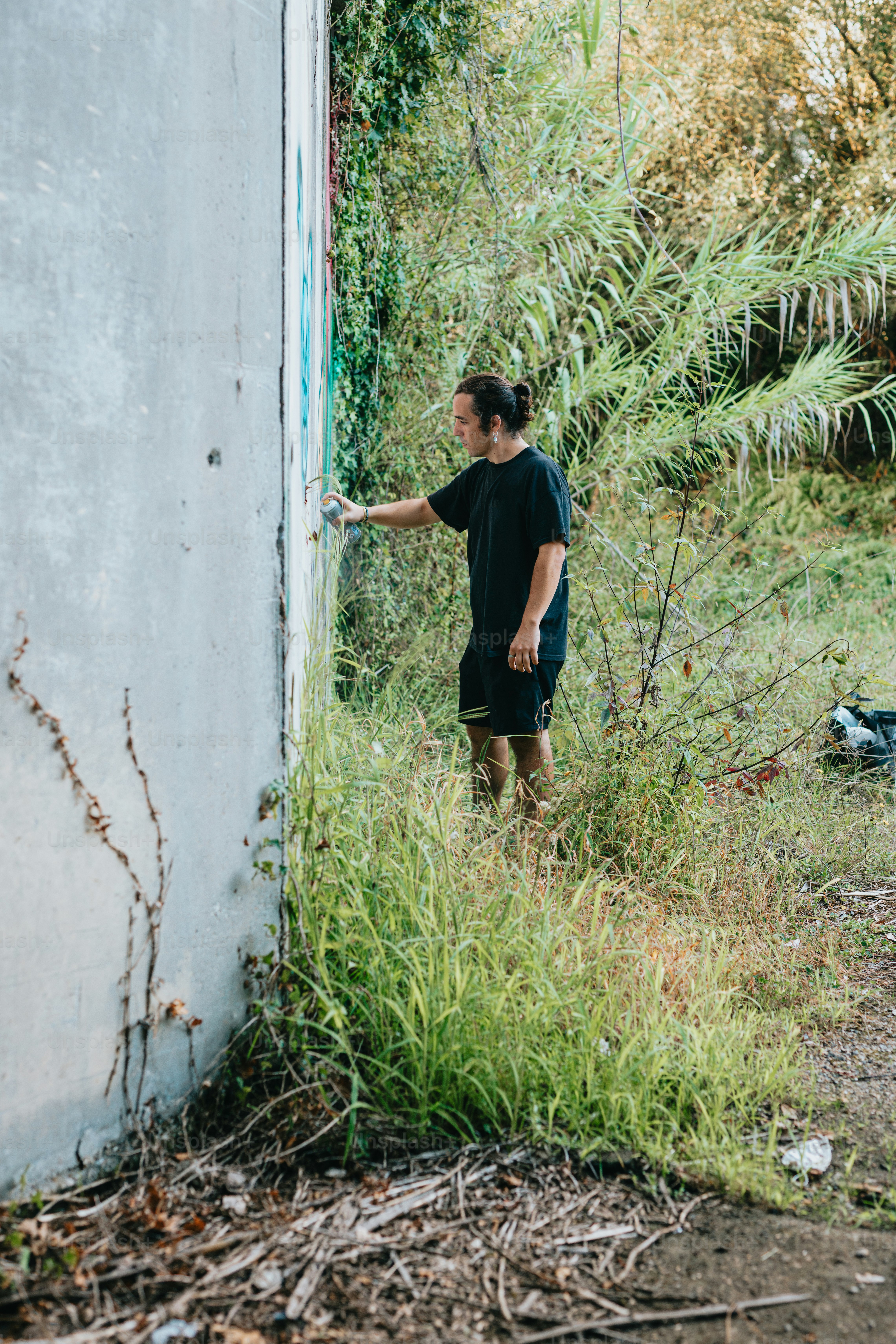 a man standing next to a building near a bush
