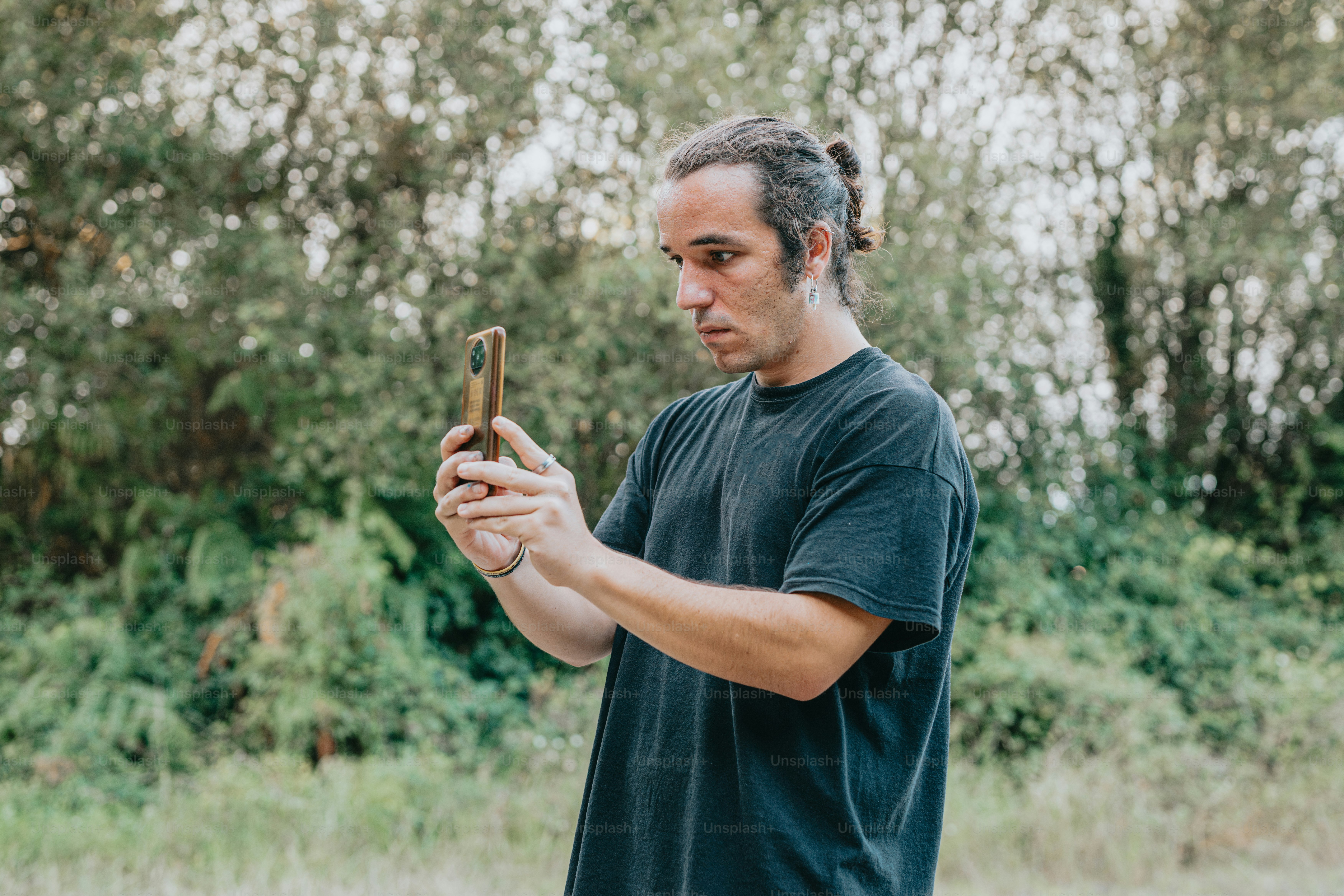 a man standing in a field holding a cell phone