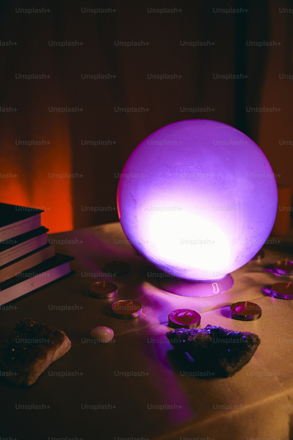 a table topped with a purple light next to a stack of books