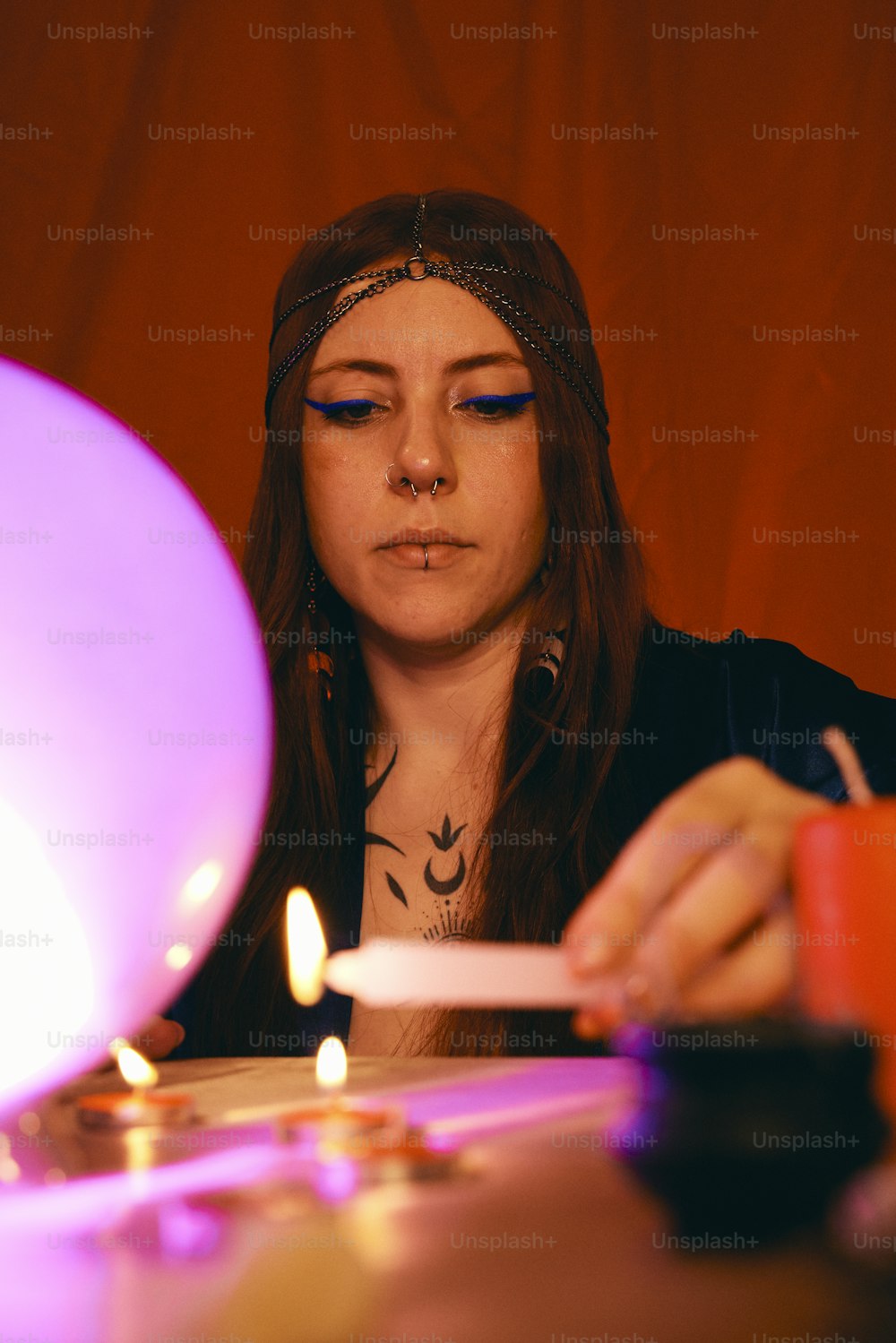 uma mulher sentada em uma mesa com uma vela na mão