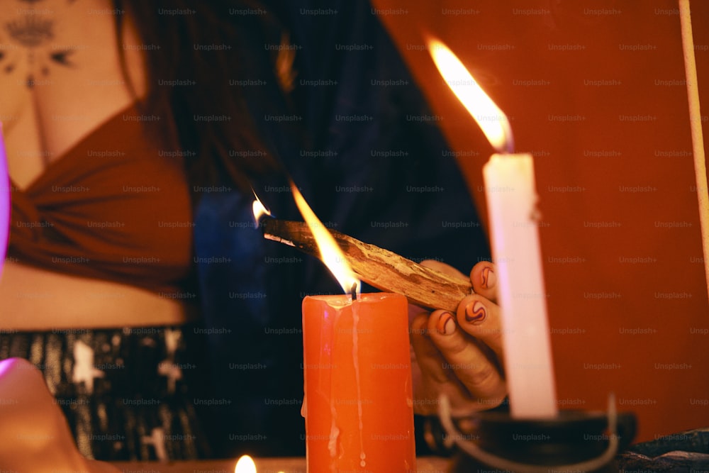 a person lighting a candle with a stick