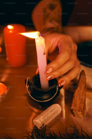 a woman holding a lit candle on top of a table